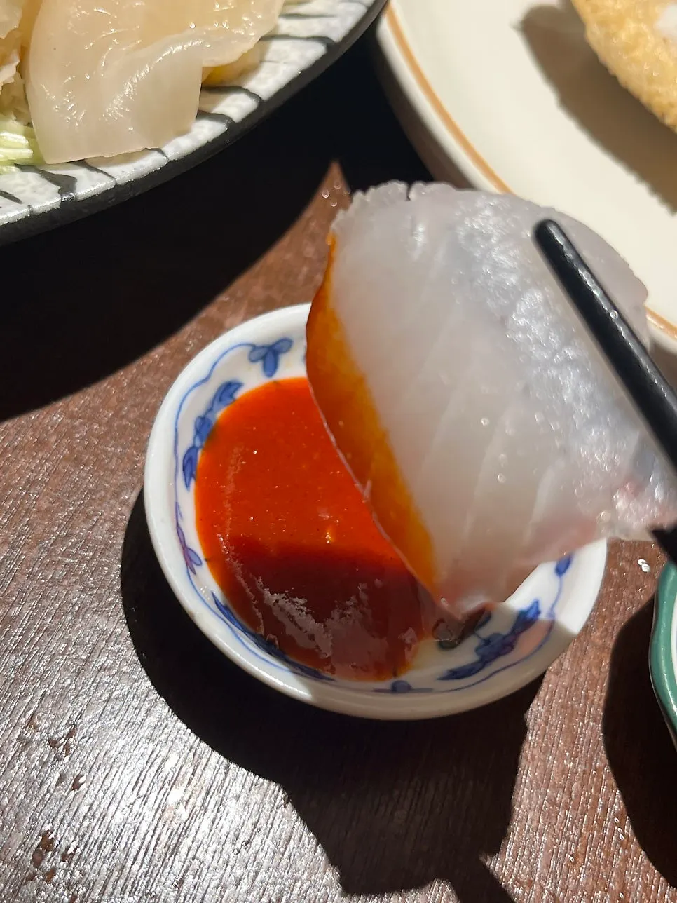 Piece of flounder sashimi dipped in chojang sauce
