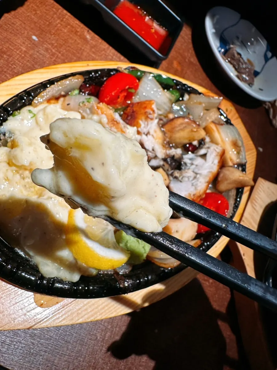 A piece of grilled mero held with chopsticks