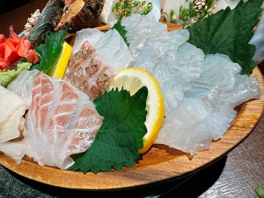 A meal spread with sashimi and chicken dishes