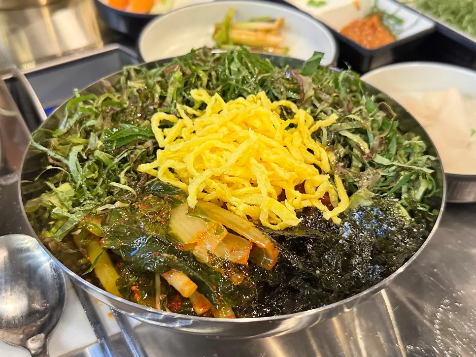 Yeolmu bibim guksu loaded with yeolmu, perilla leaves, and egg strips
