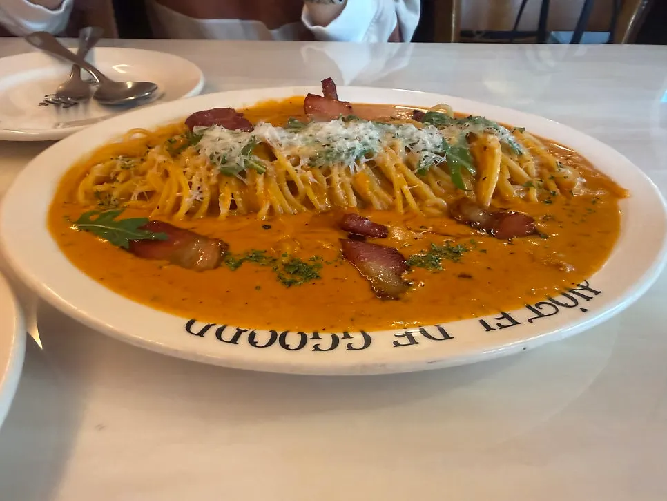 Close-up of thick-cut bacon on rosé pasta