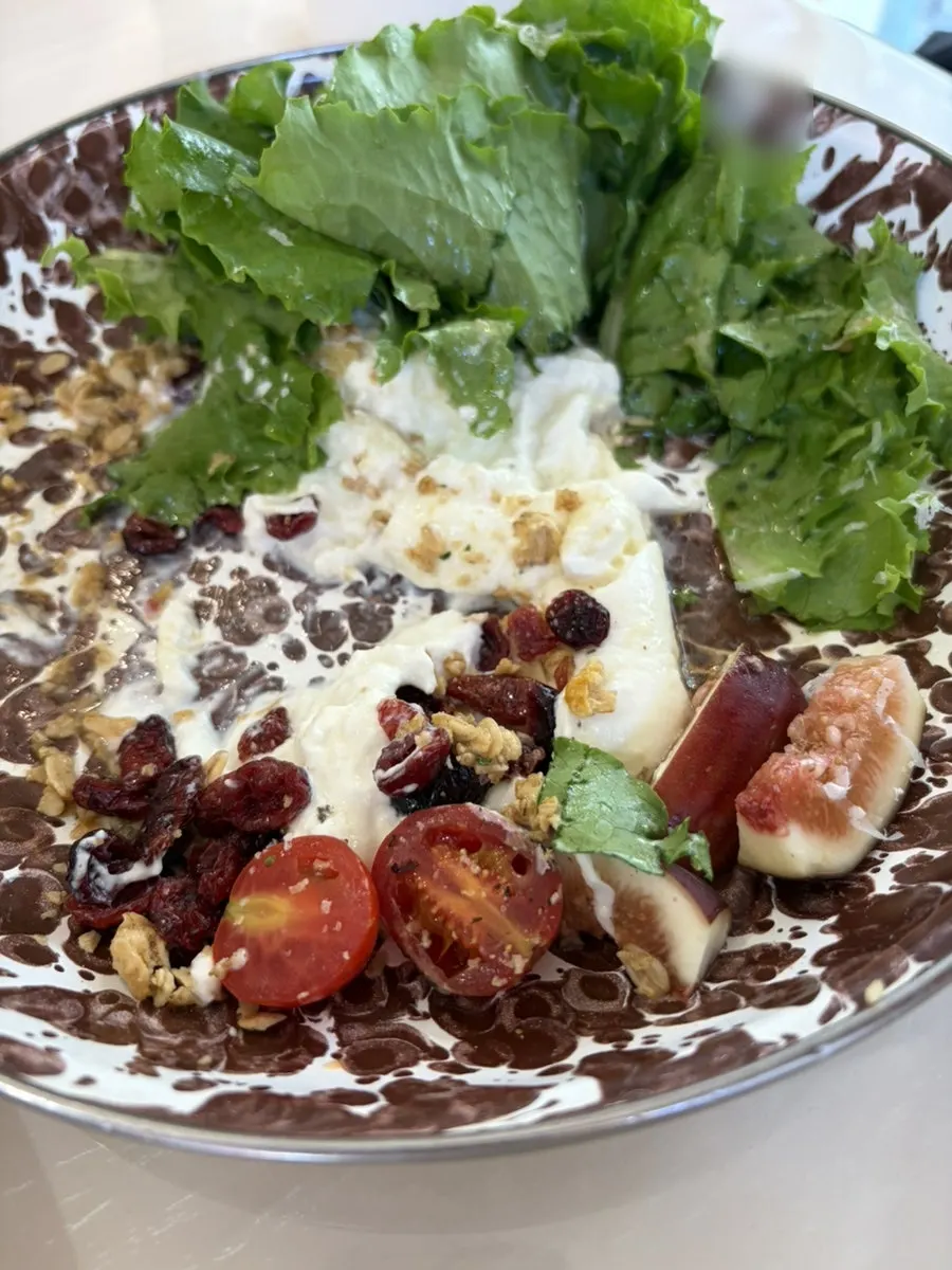 Serving a portion of the burrata seasonal fruit salad