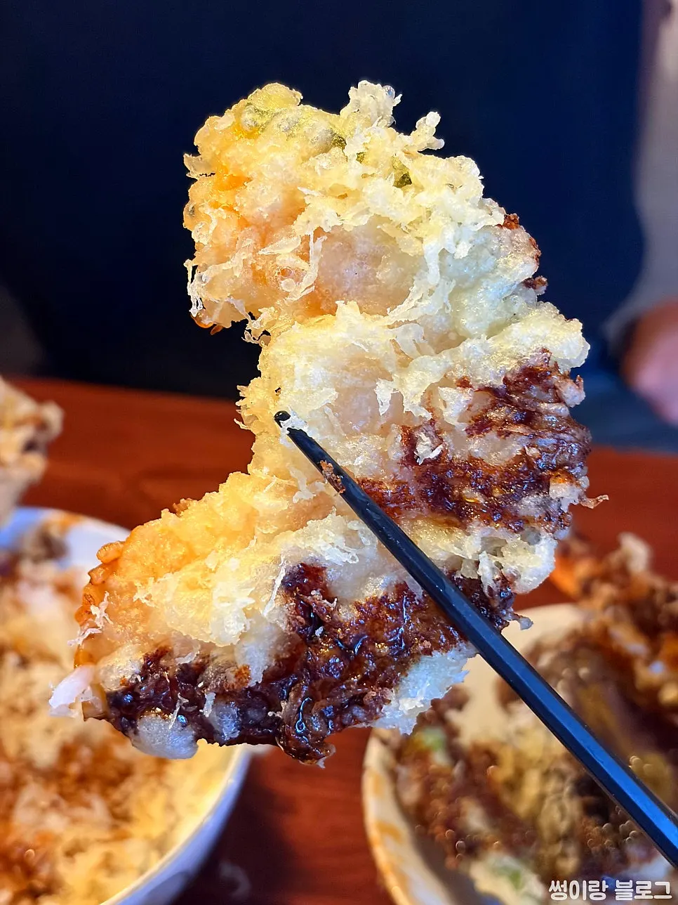 Picking up a piece of shrimp tempura from the tendon