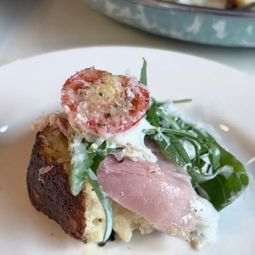 A bite of French toast topped with sauce and arugula