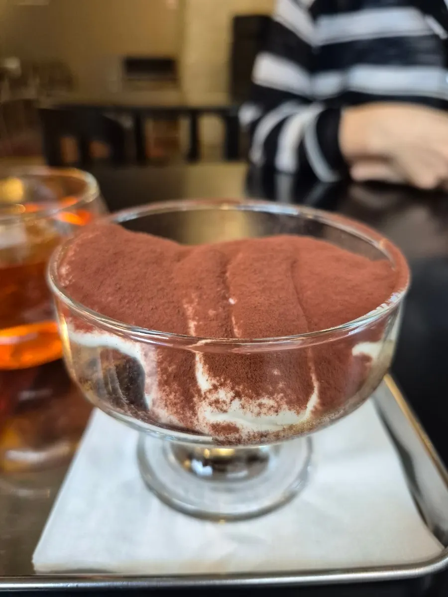 Tiramisu in a glass cup piled high with cocoa powder