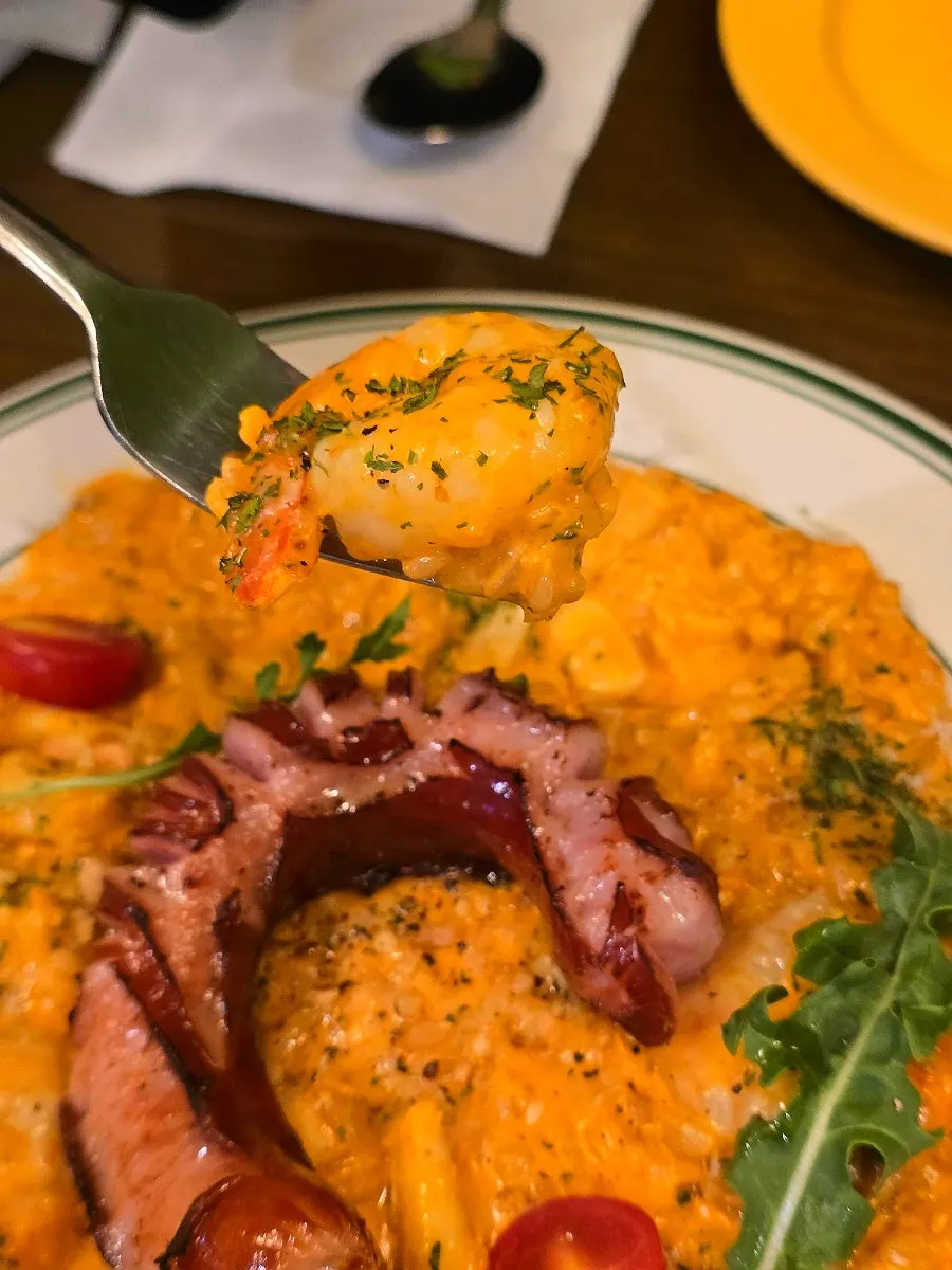 A spoonful of rosé risotto with shrimp and squid