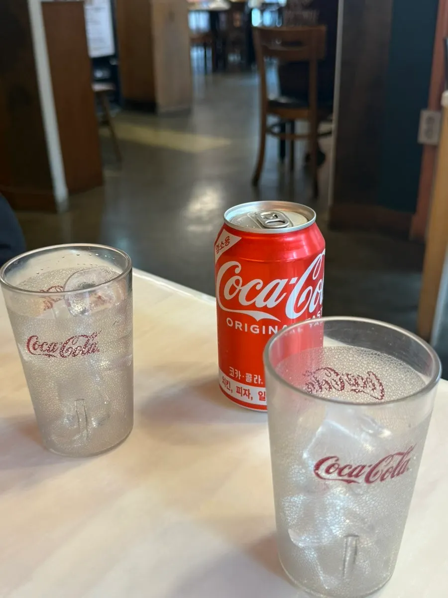 Two ice-filled cups prepared alongside cola