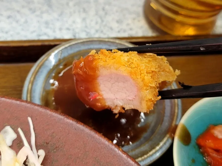 A piece of hirekatsu held with chopsticks