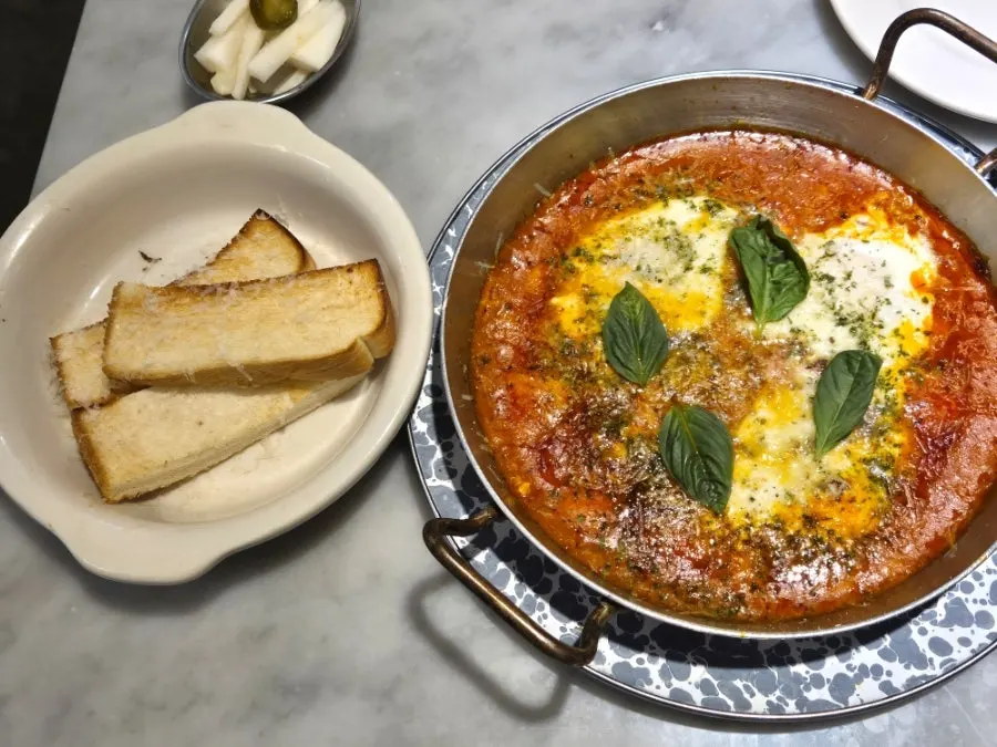 A plate of egg in hell topped with basil