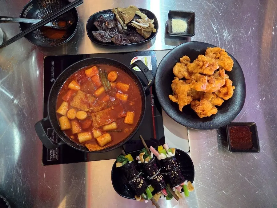 Table spread of rice-cake tteokbokki, chicken, sundae and gimbap