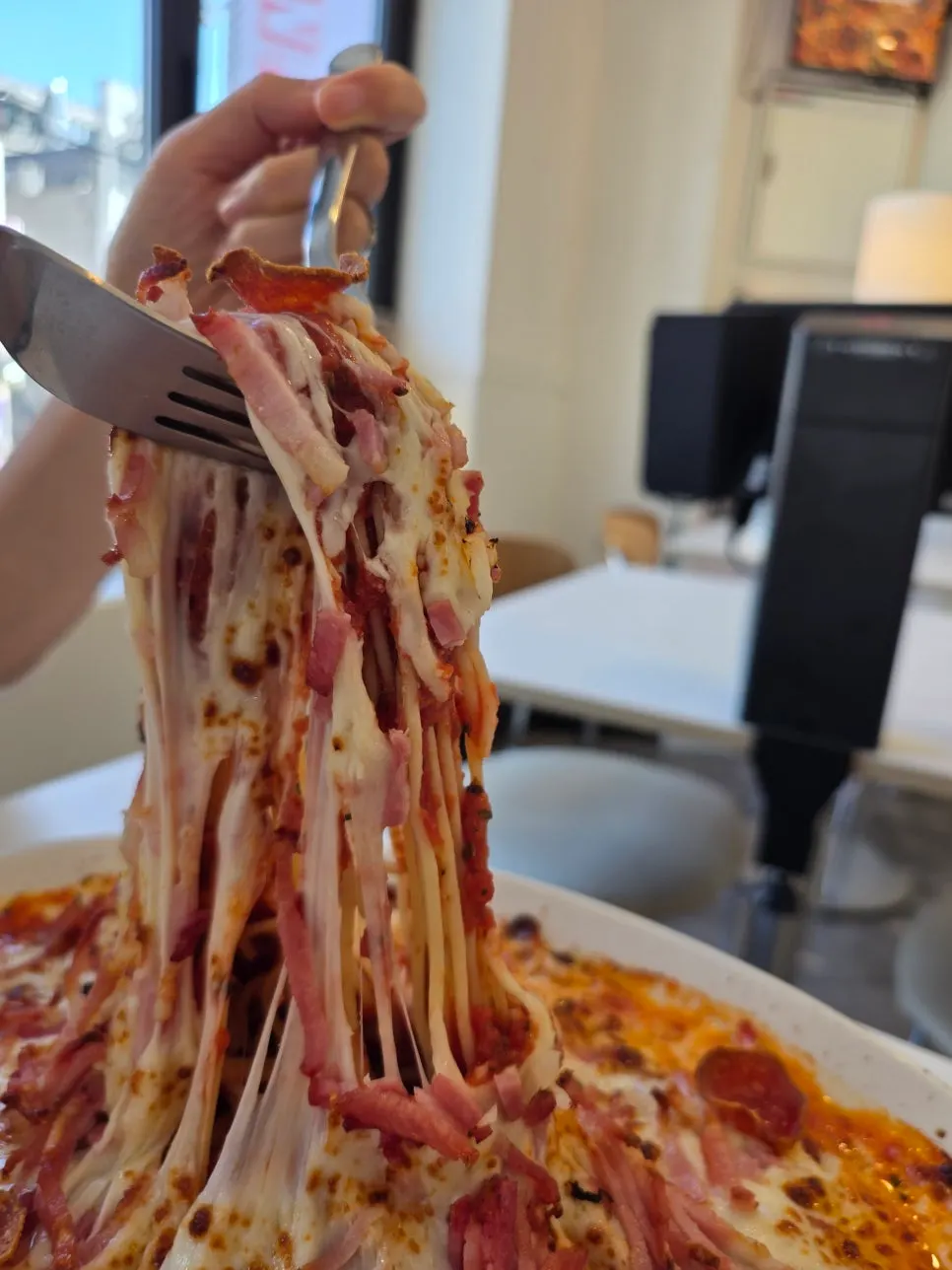 Stretchy cheese pull on the classic oven pasta at Sunny's Pizza Market