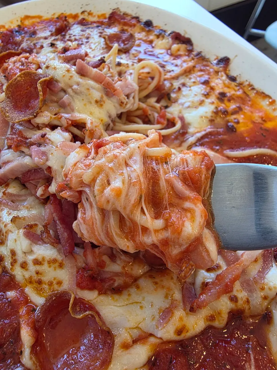 Fork lifting cheese from the oven pasta