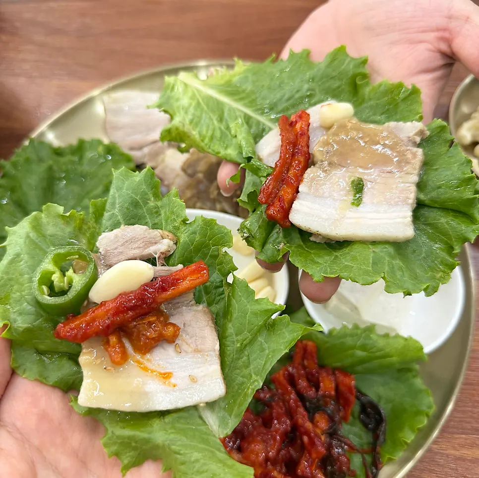 A bossam wrap topped with pickled radish strips