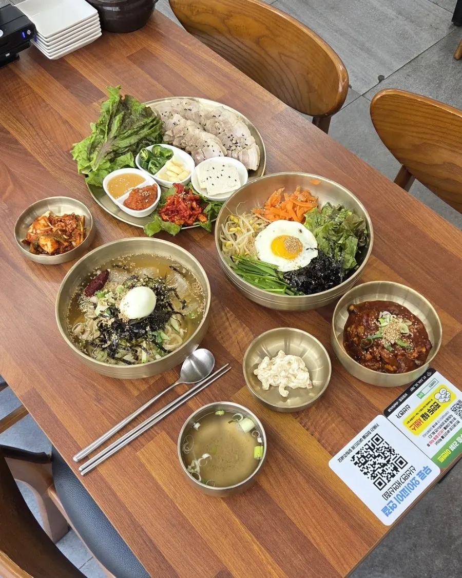 Table spread of cold kalguksu, octopus bibimbap, and small bossam