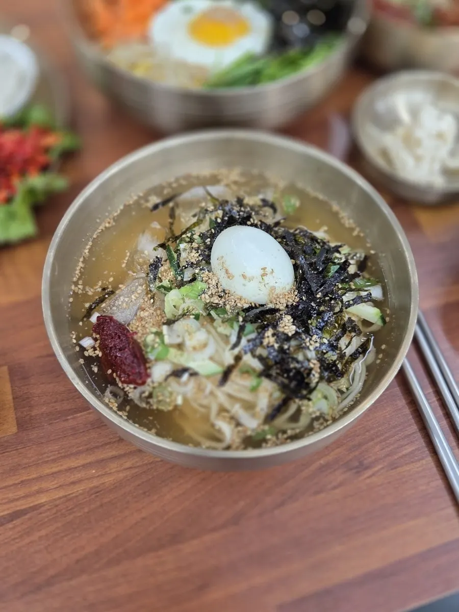 Cold kalguksu in a brass bowl topped with boiled egg