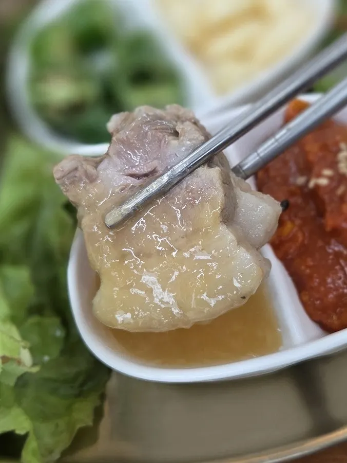 A piece of bossam pork dipped in garlic sauce
