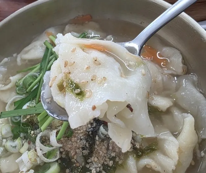 A bowl of hand-torn sujebi topped with sesame seeds