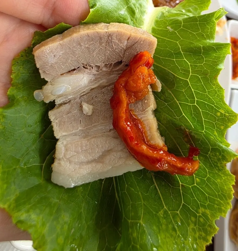 A wrap of boiled pork topped with dried radish strips