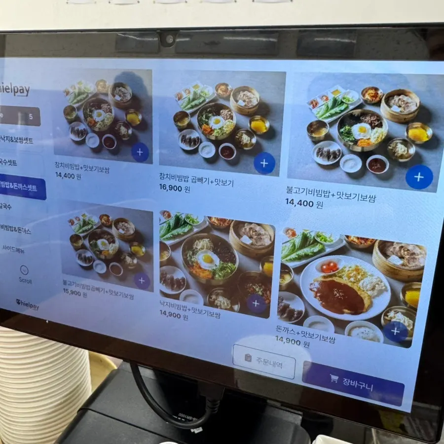 Menu board showing anchovy kalguksu, bibimbap, and other dishes