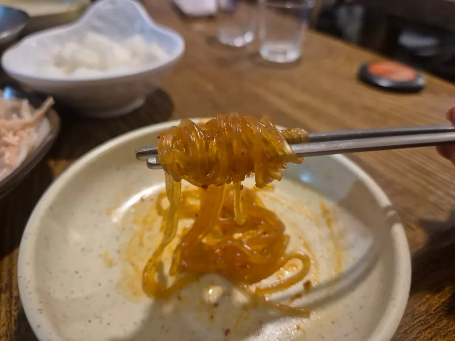 Un bocado de fideos de vidrio empapados en la salsa del dakdoritang