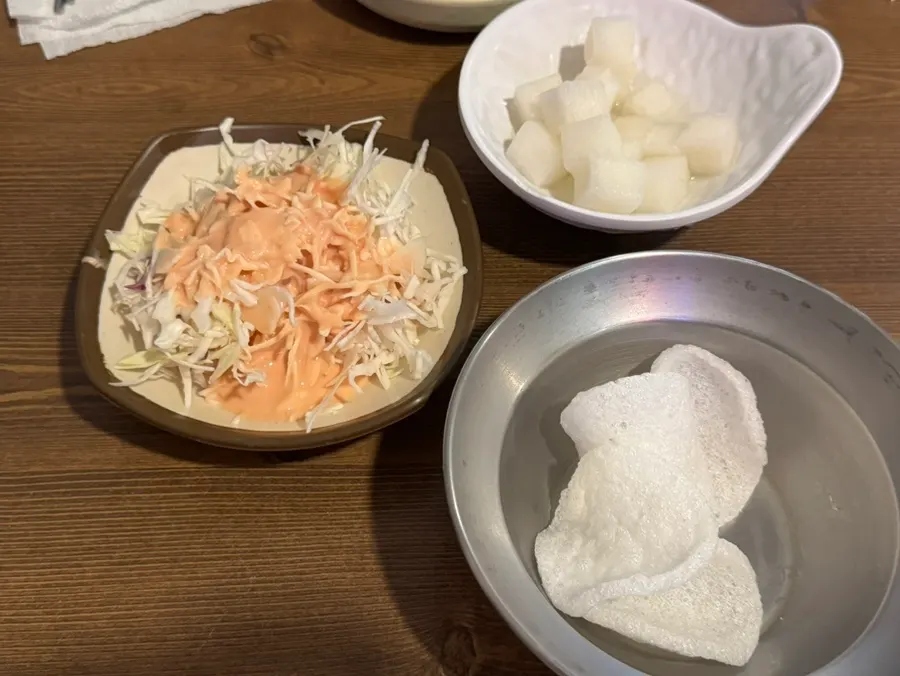 Cabbage salad, shrimp chips, and pickled radish side dishes
