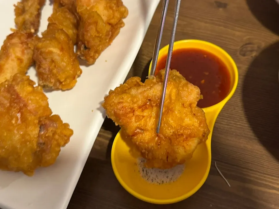 A piece of fried chicken dipped in seasoning sauce
