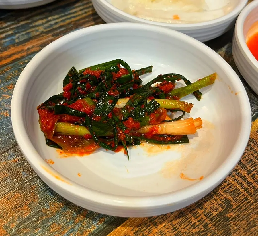Seasoned green onion salad served alongside the meat