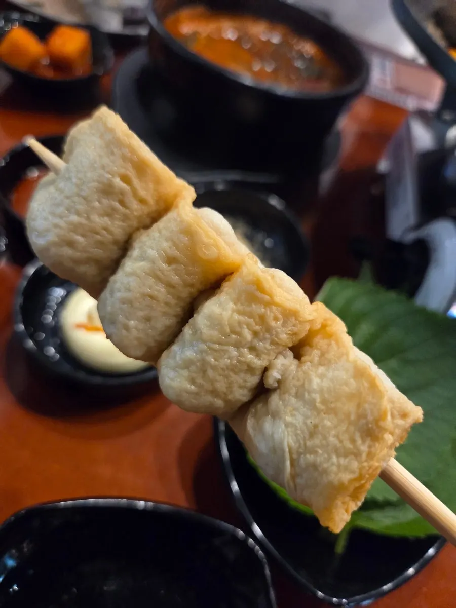A piece of gopchang dipped in the special sauce