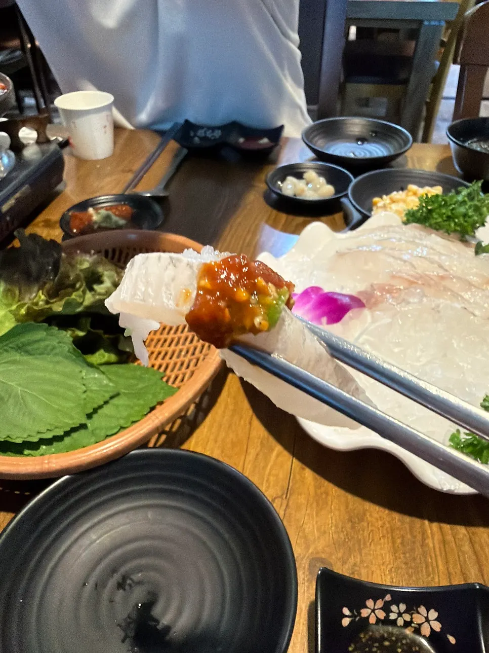A piece of flounder sashimi dipped in wasabi soy sauce