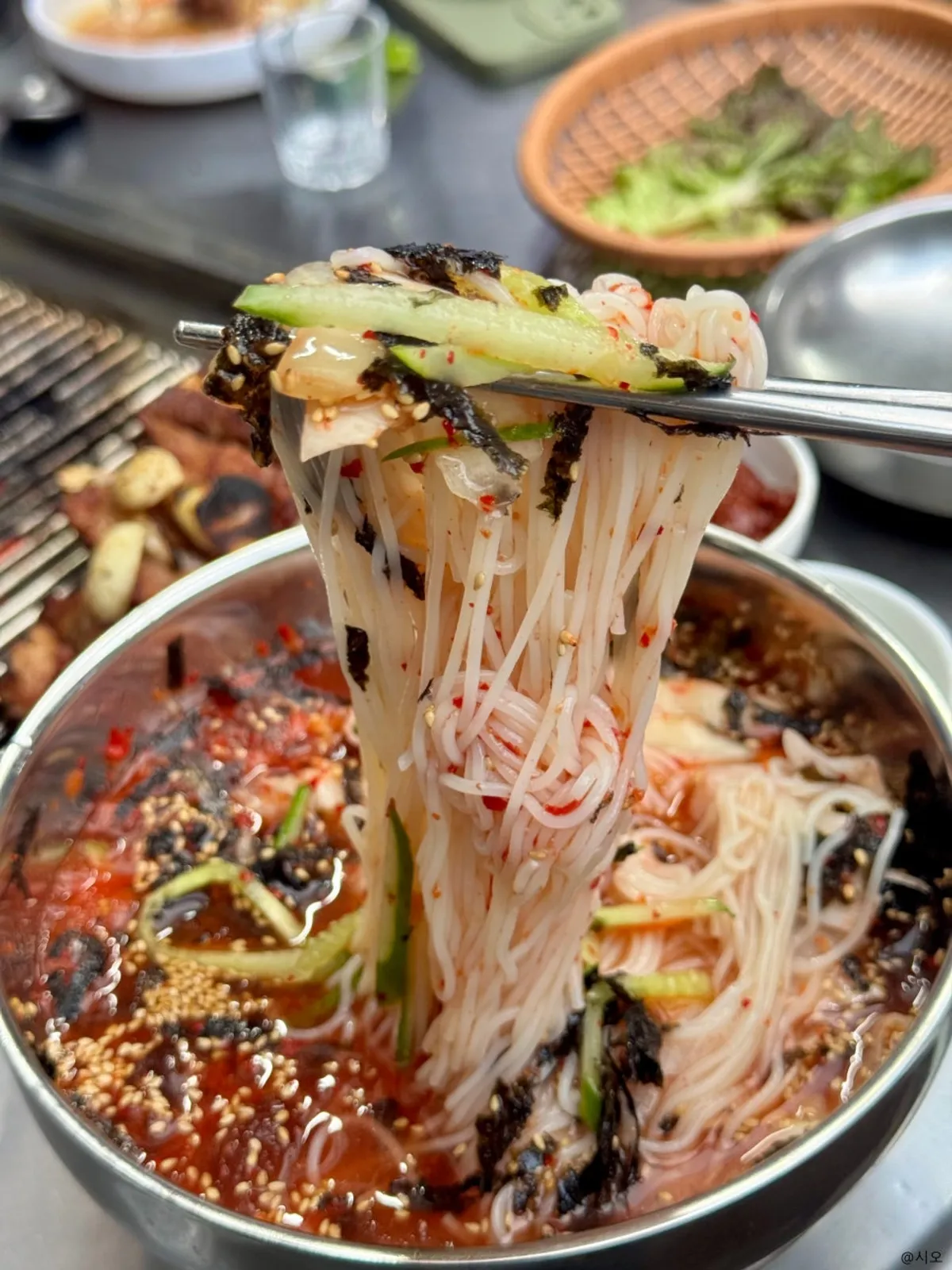 Kimchi noodle soup topped with kimchi, cucumber, and seaweed flakes