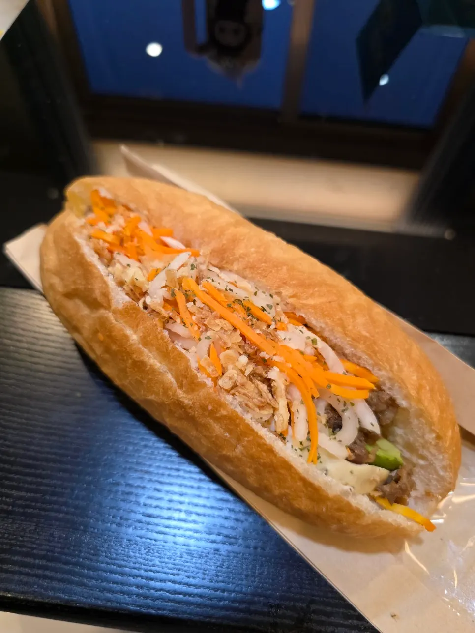 Cross-section of banh mi with meat, pickled vegetables, and avocado