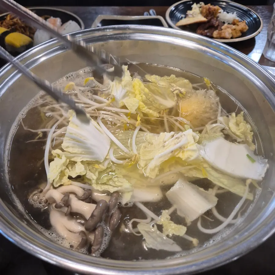 Shabu-shabu vegetables going into boiling broth