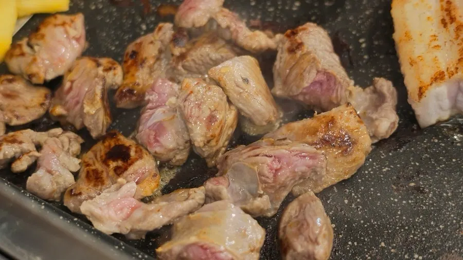 Staff member grilling samgyeopsal on the table grill