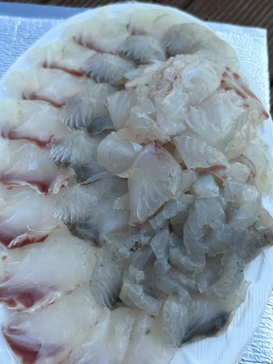 Plate packed edge to edge with red sea bream and sea bass sashimi
