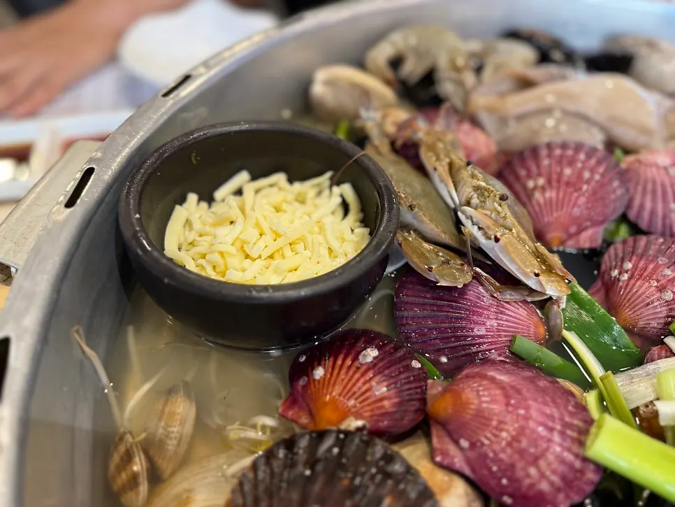 Hot pot densely packed with half-shell clam, scallops, mussels, and shrimp