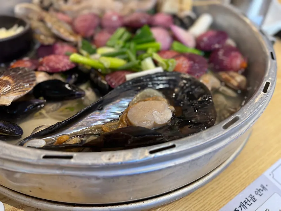 Scallop dipped into cheese in an earthenware pot
