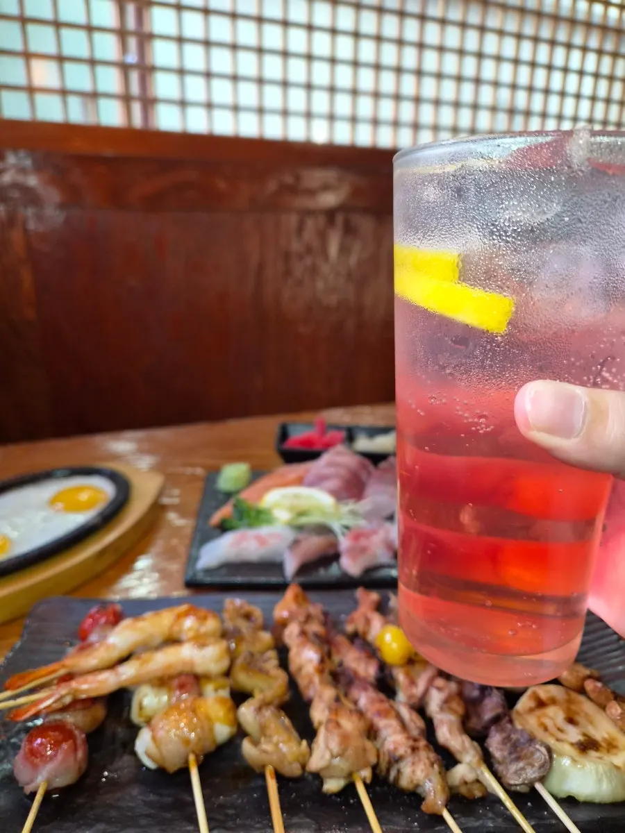 Table with sashimi, skewers, and a highball