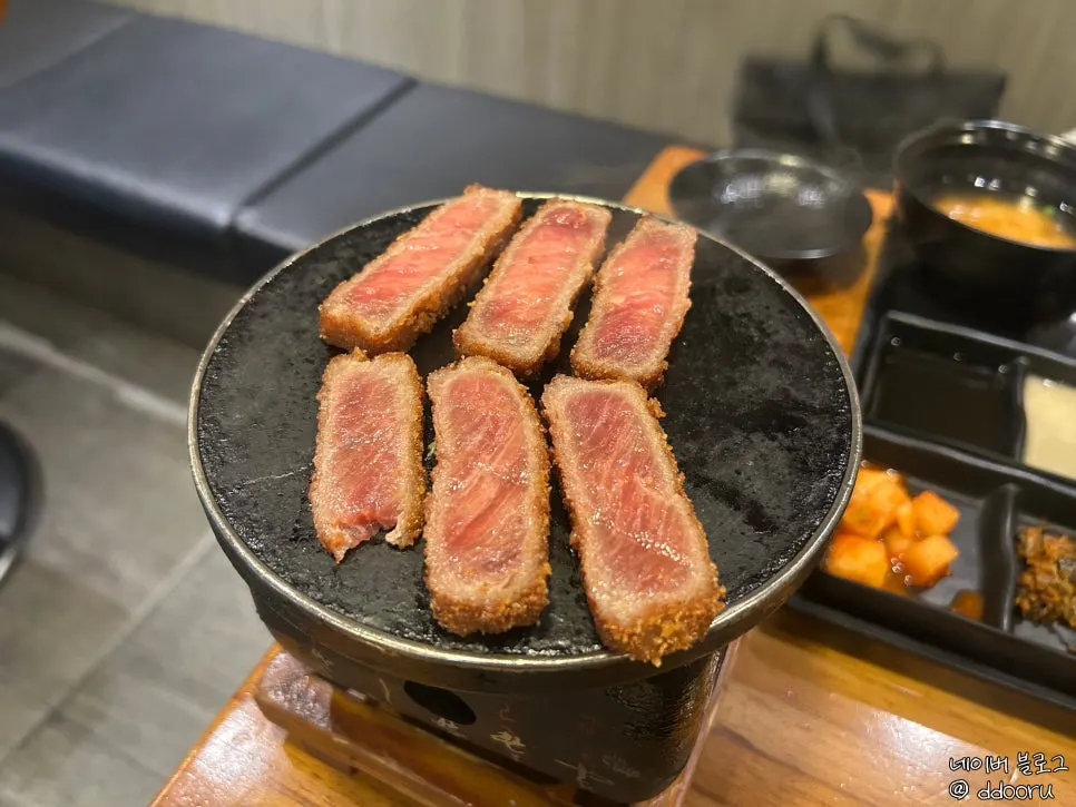 젓가락으로 든 이자와 규카츠 한 점