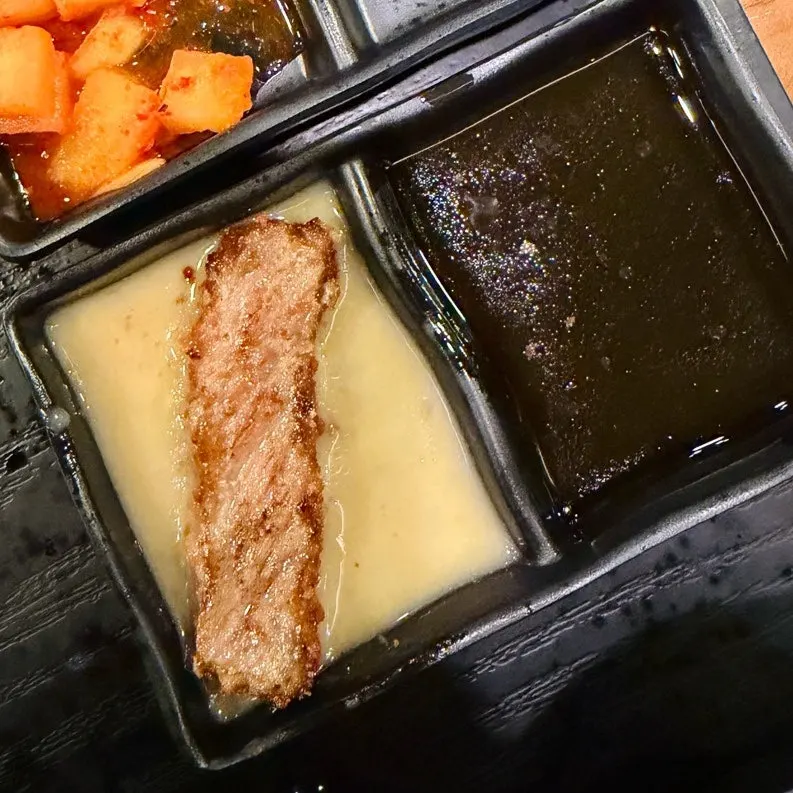 특제 노란 소스에 찍은 규카츠 한 조각