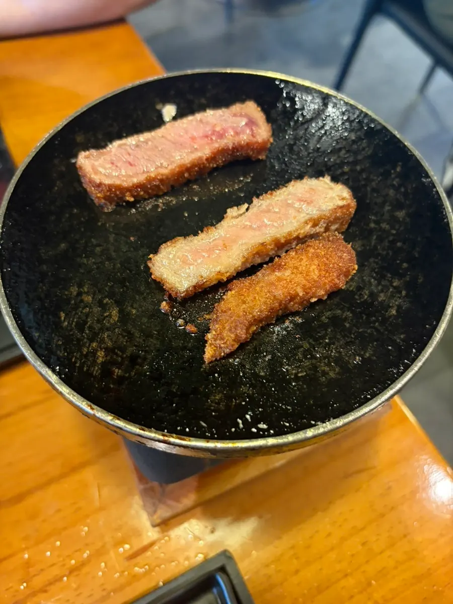 A piece of gyukatsu about to be dipped in salt