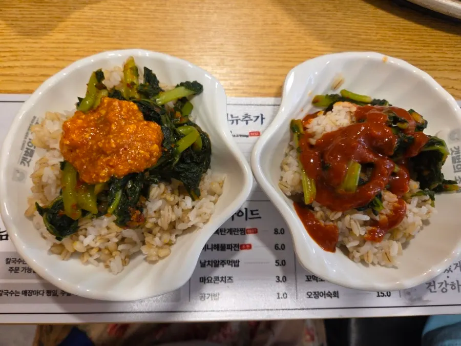 Two bowls of yeolmu barley rice made with doenjang and chogochujang sauce