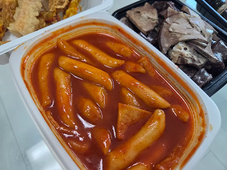 Tteokbokki and fried snacks laid out after opening the lid
