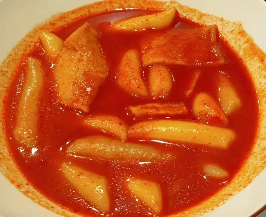 Close-up of chewy rice cakes coated in tteokbokki sauce