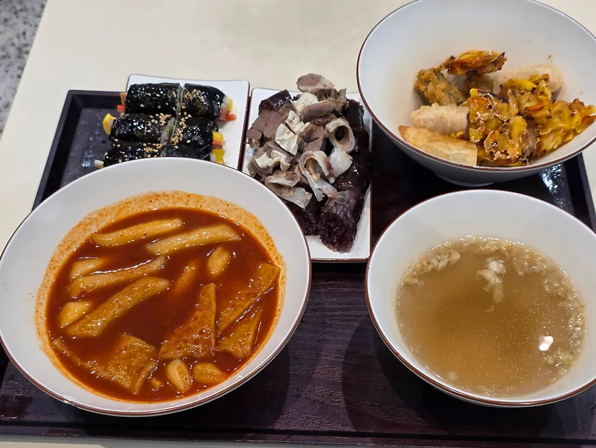 Full table spread of the Hyeonseonine Set with bright red broth tteokbokki