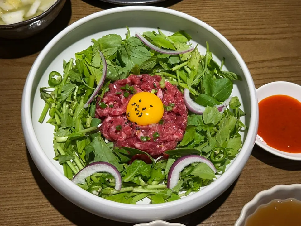 Bibimbap topped with hanwoo yukhoe and minari