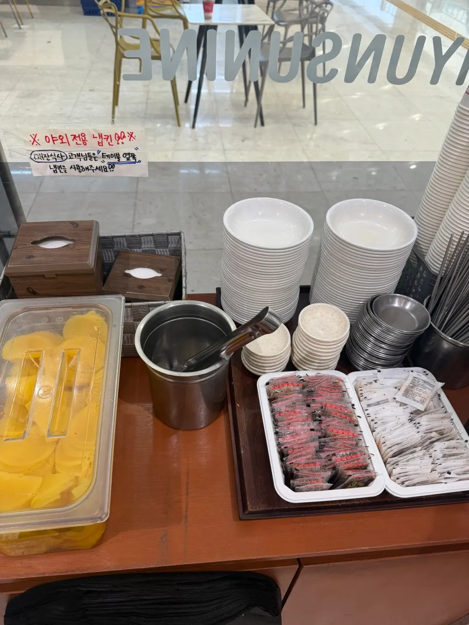 Self-service bar with plates, chopsticks, and pickled radish