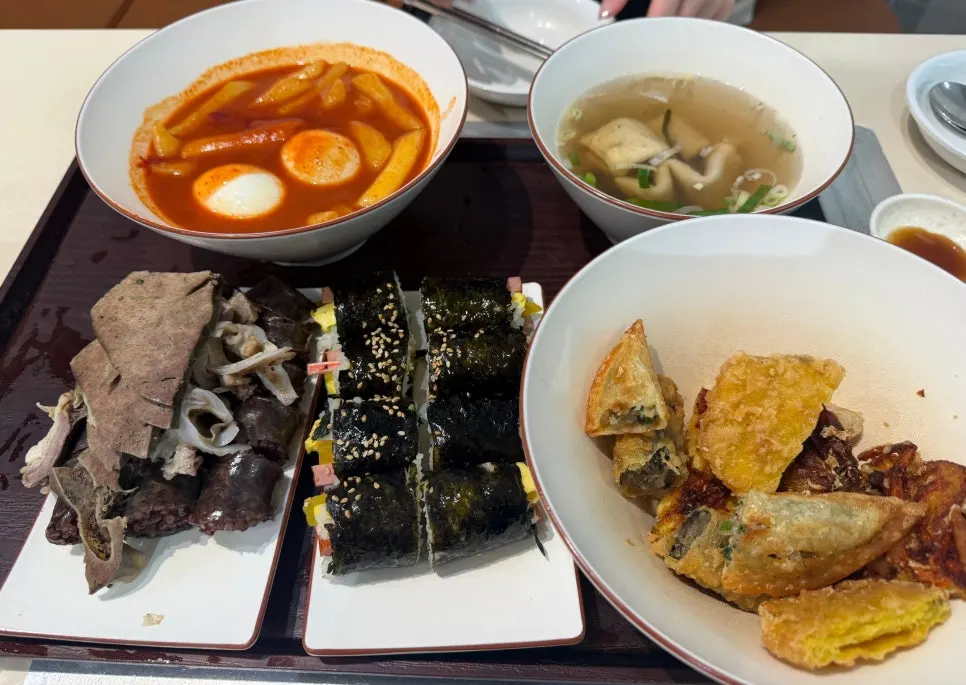 Full spread of the Hyeonseonine set with tteokbokki, fried snacks, sundae, and gimbap