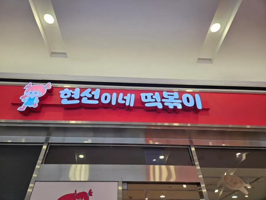 양갈래 머리 소녀 캐릭터가 그려진 현선이네 프리미엄 간판