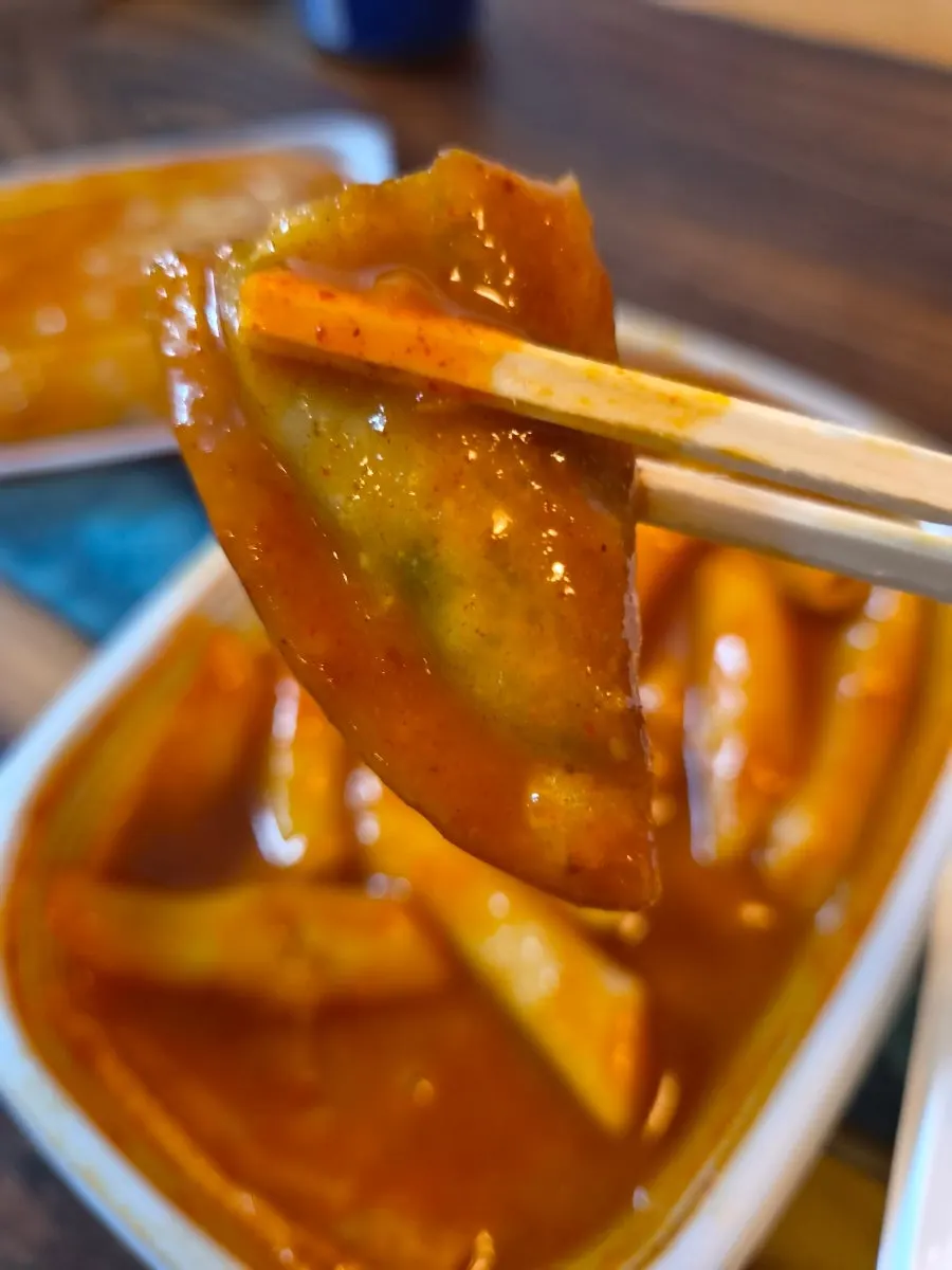 Fried snack dipped in tteokbokki sauce