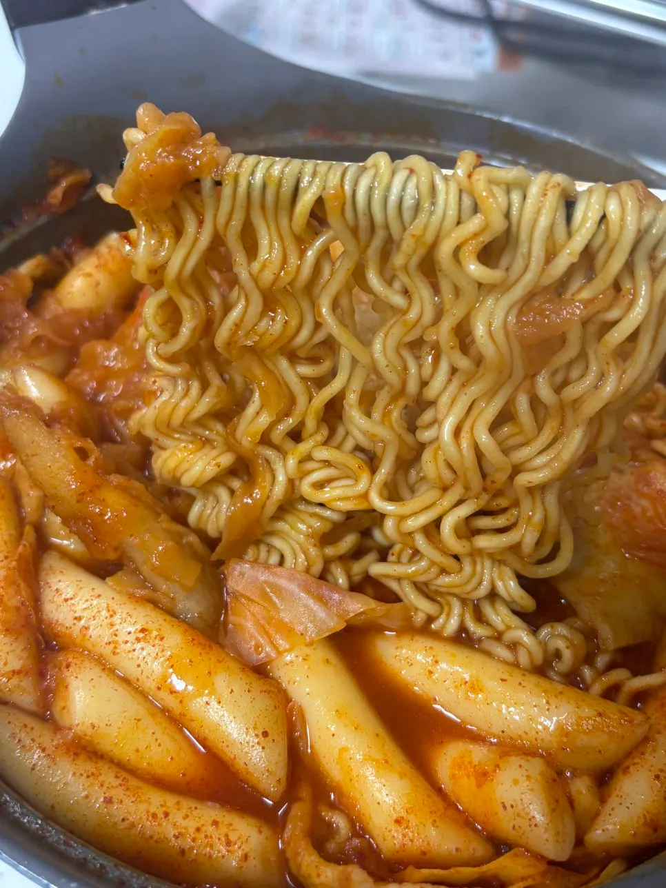 A bite of instant tteokbokki coated in spicy-sweet sauce